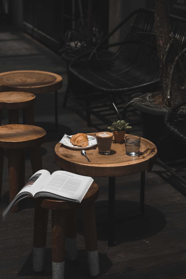 Coffee cup on a small table with a chair next to it that has a book on it